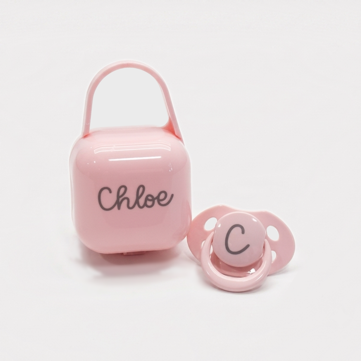 Chupete rosa con su cajita portachupetes a juego, personalizados con el nombre y la inicial del bebé